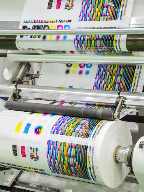 Large offset printing press or magazine running a long roll off paper in production line of industrial printer machine.